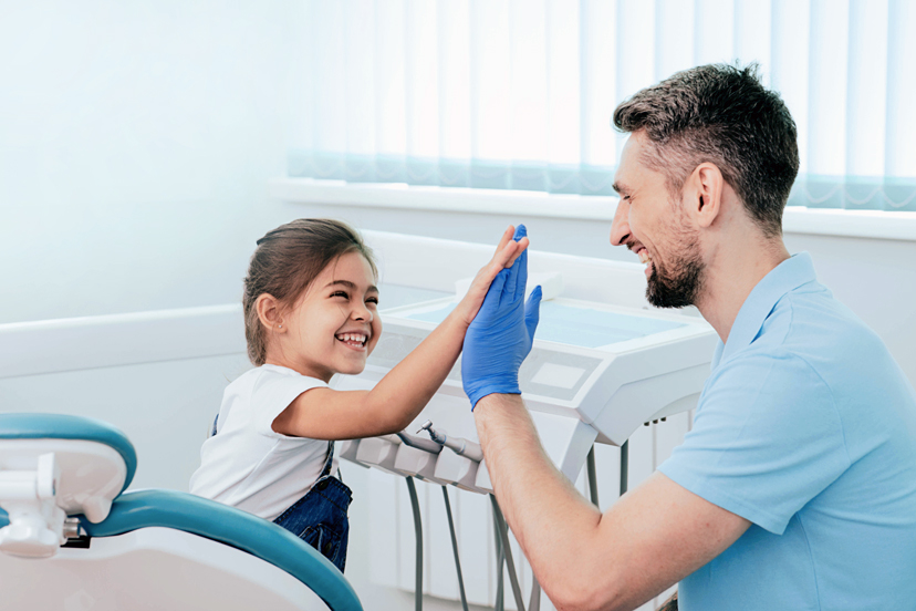 Zahnarzt fröhlich bei der Behandlung eines Mädchens